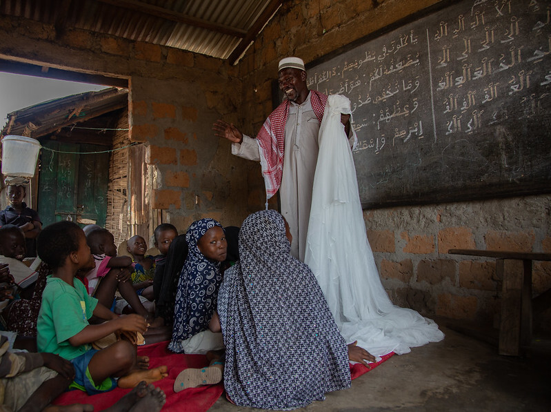 Religious leader holds malaria net while speaking to students about about the importance of sleeping under nets to prevent malaria 