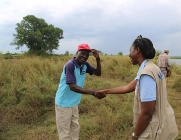 USAID representative shaking hands with a man in a field