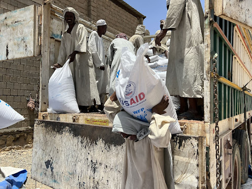 Community members unload bags of grain from truck