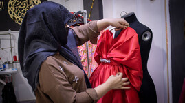 Owner of Al Basma Al Aneeya House of Fashion inspects a new dress design.