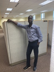 IBRAHIM FOFANAH POSES IN AN OFFICE CUBICLE AT USAID/GUINEA