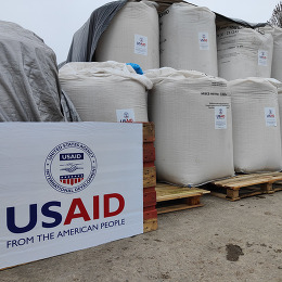Bags of grain in Ukraine behind a sign with the USAID logo.