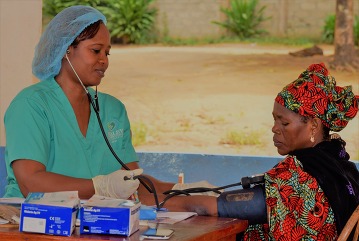 MANJA TAYLOR CHECKS PATIENT’S BLOOD PRESSURE AT DANIEL SULLIVAN HEALTH CLINIC IN SIERRA LEONE.