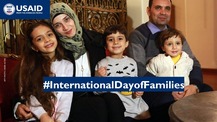 A woman, man, and their three children smile at the camera. The text "International Day of Families" is overwritten on the image.