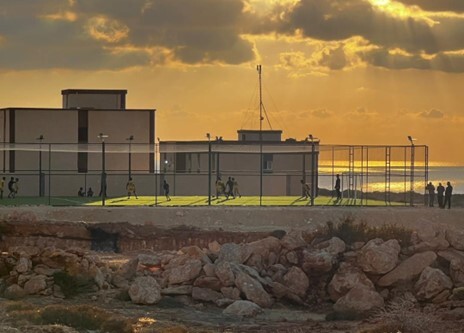 Chiildren play on the Assahel soccer field as the sun sets.