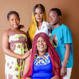 A woman and her two siblings pose for a family portrait with their mother who is seated in front of them.
