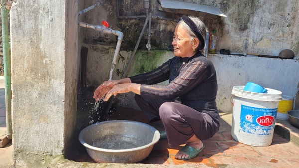 Woman smiles while washing her hands over a water basin.