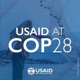 Text reading "USAID at COP28" on top of an image woman fishing with a blue background. 