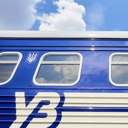 Closeup of a deep blue railcar with Ukrainian crest against a light blue sky. 