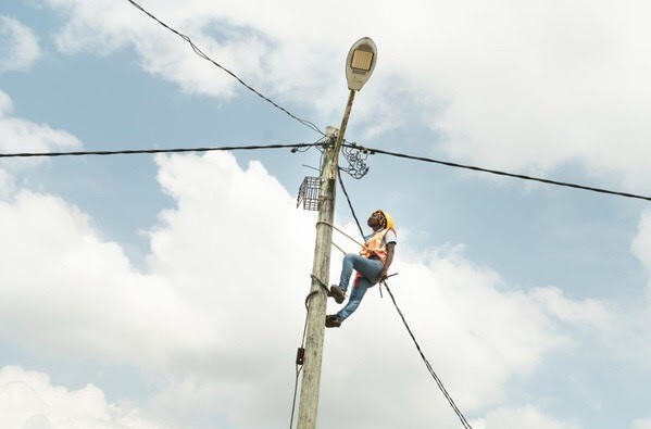 Woman in hardhat climbs utility pole