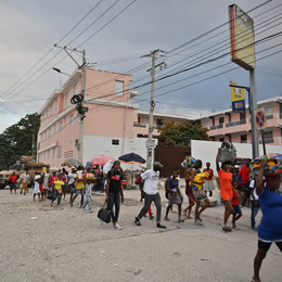 A large group of people walk with their belongings down a street in Haiti