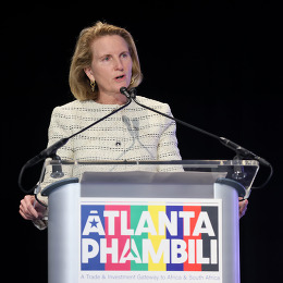 A woman speaks at a podium. On the podium is a multicoloured "Atlanta Phambili" sign.