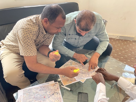 Members of the Murzuq Steering Committee review maps of damaged neighborhoods. 