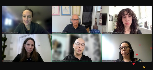 Screenshot of virtual event with 4 female, 2 male speakers in a 3x2 grid. The bottom middle speaker has a green box around him; he is speaking.