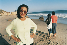 Woman standing on beach with hands on her hips, people standing in background