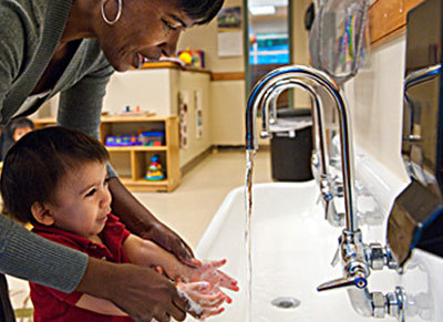 young boy and teacher washing hands