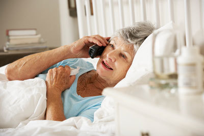 Woman laying sick in bed making phone call