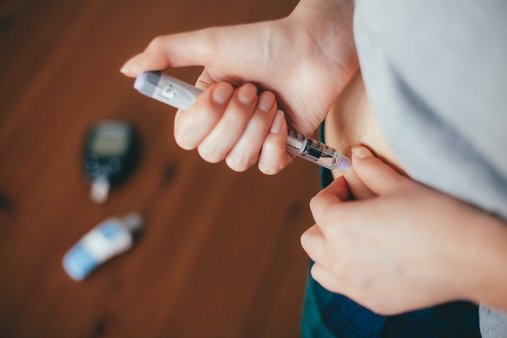 Person injecting insulin into their a pinch of skin on their abdomen