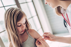 girl getting band aid from health professional