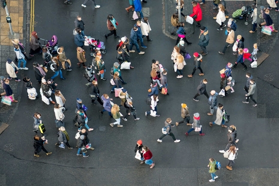 People walking across a busy intersection, photographed from above