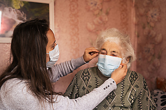 Woman putting a mask on an elderly woman