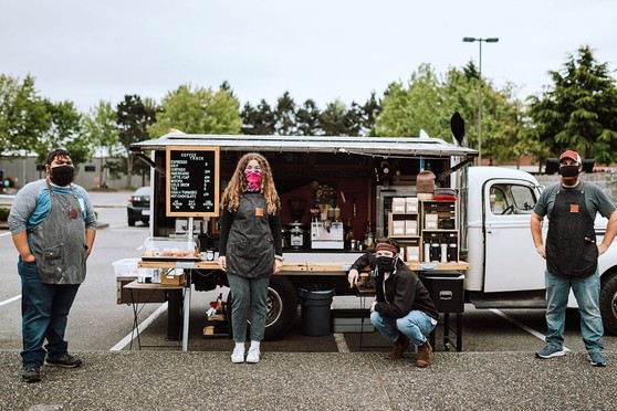 Workers set up their food truck in a parking lot to service patrons.