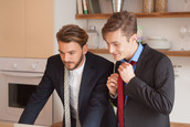 Two men getting ready for work together in their house.