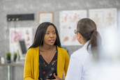 A young adult female patient discusses personal health issues with her physician.