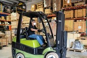 A worker drives a forklift around a warehouse.