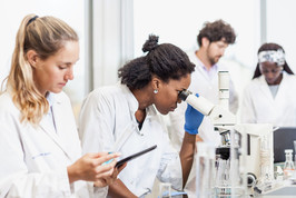 Two female scientists in to foreground record scientific observations.