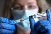 A nurse prepares a syringe with a dose of a COVID-19 vaccine.