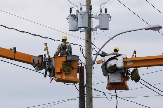 Electric company contractors perform work on power lines.