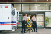 Paramedics wheel a person on a stretcher into an emergency room.