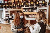 Two restaurant employees wearing facemasks speak to each other.