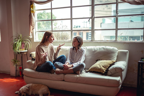 A mother sits at home on her couch with her daughter.