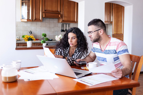 A couple sits at a table together and works on planning out their finances.