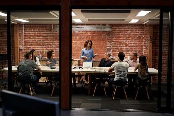 A woman stands up at her business meeting to make a presentation to her colleagues.