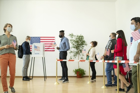 People stand in line to vote while social distancing and wearing face masks.