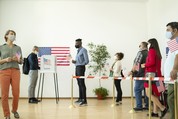 People stand in line to vote while social distancing and wearing face masks.