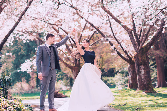 A married couple clasp their hands together up in the air in an outdoor setting.