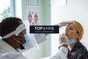 A medical practitioner performs a nasal swab test on a female patient.