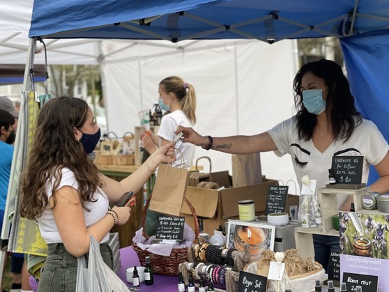 Flea market boutique owners do business with customers, while everyone wears face masks during the coronavirus pandemic.