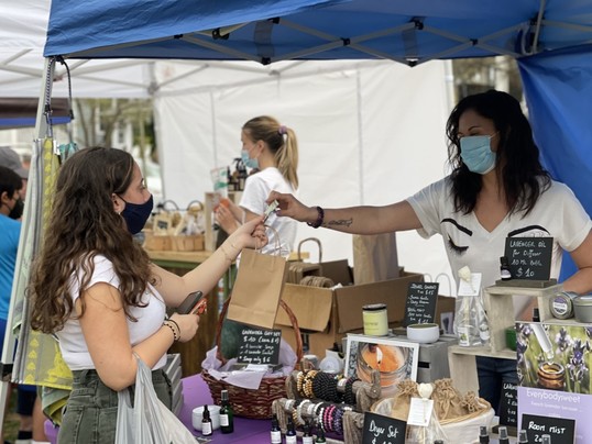 Flea market boutique owners do business with customers, while everyone wears face masks during the coronavirus pandemic.