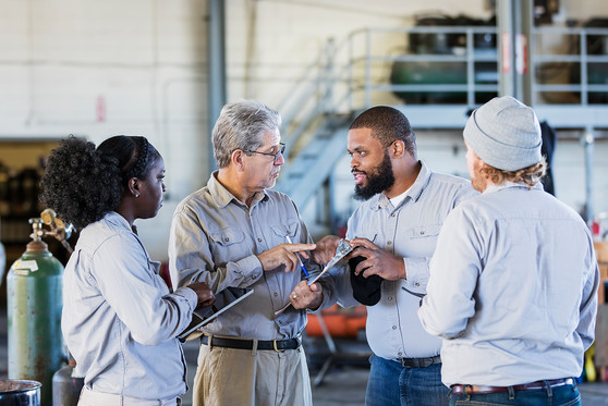 Workers meet with each other to discuss a task.