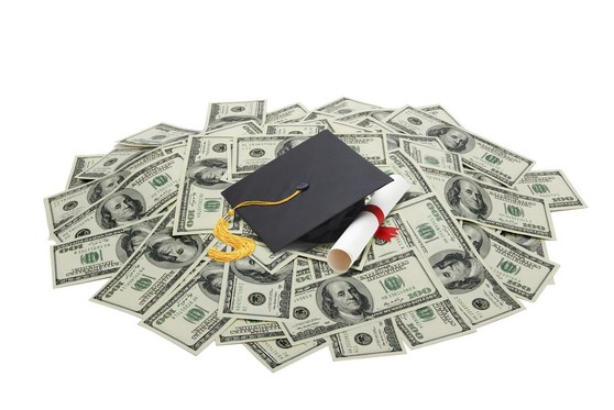 A mortarboard and diploma sitting on top of a pile of $100 bills