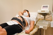 A pregnant woman lays down on an examination table while hooked up to monitors.