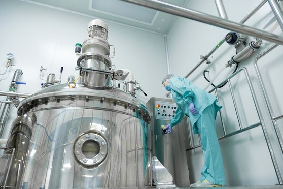 A pharmaceutical worker checks a device at a pharmaceutical manufacturing plant.