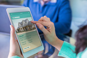 A woman looks at a real estate property listing on her tablet.