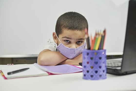 A child sitting at his desk taking a break from schoolwork.