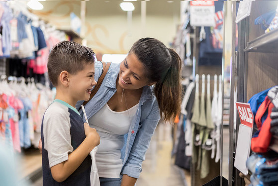 A mother and her son look for new clothes at a store.